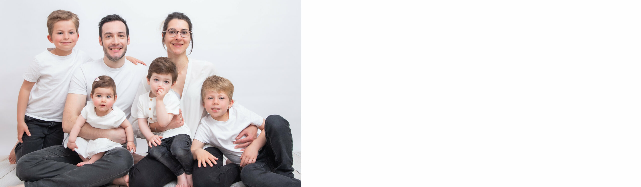 Photo réalisée en studio en couleur famille de 5 personnes tous souriants et habillés en blanc sur fond blanc